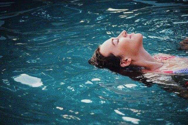 Chica relajada mientras sumerge una parte de su pelo en la piscina