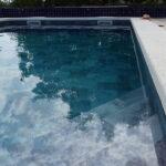 Escalera de obra en una piscina existente: qué revisar antes de la reforma Escalera de obra en una piscina revestida con lámina armada gris, situada en una esquina del vaso.